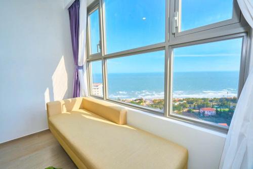 a couch in a room with a large window at The Sóng Vung Tau Apartment - Pool Near Sea in Vung Tau