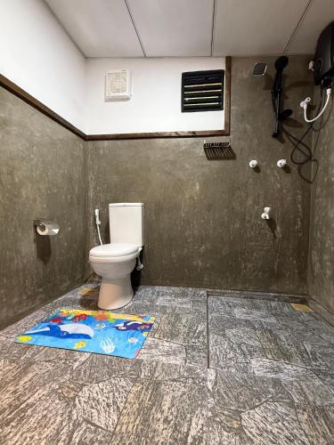 a bathroom with a toilet and a rug on the floor at Sigiriya Lantern Homestay in Sigiriya