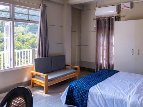 a bedroom with a bed and a chair and a window at Teecee in Āīzawl
