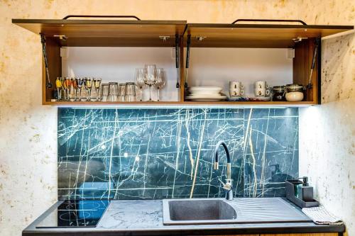 a kitchen with a sink and a green tiled wall at Apartmani Tiske noći in Bečej