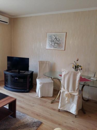 een woonkamer met een tafel en stoelen en een televisie bij City Centre Apartment in Győr