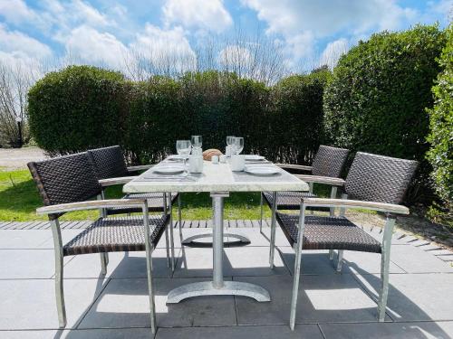 a table and chairs with glasses on a patio at Apartment Pangani Teichhof Fehmarn in Wenkendorf