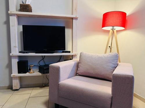 a living room with a chair and a television at Apartment Pangani Teichhof Fehmarn in Wenkendorf