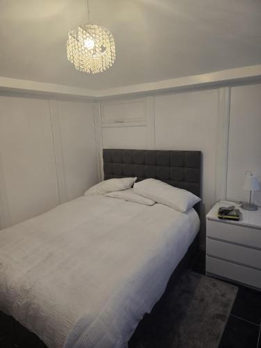 a bedroom with a large white bed with a chandelier at Kissingers Lodge in Bridgend