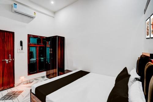 a bedroom with a white bed and a red door at Hotel O Shiv Shakti Inn in Sangrāmgarh