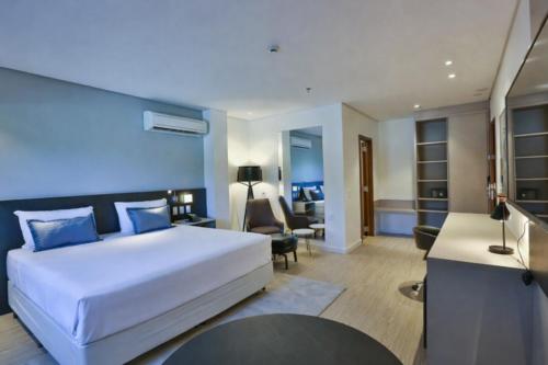 a bedroom with a large bed and a living room at Quality Hotel Blumenau in Blumenau