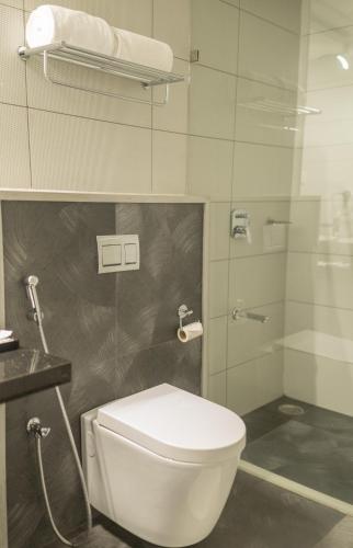a bathroom with a toilet and a glass shower at Regency Palani by GRT Hotels in Palni