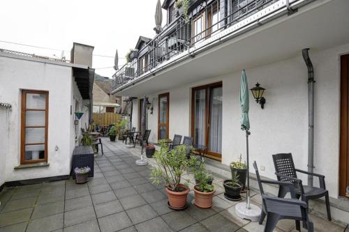 a patio with chairs and plants and an umbrella at Winzerhof Brachtendorf in Alken