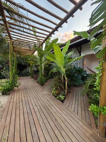 a wooden deck in a garden with a pergola at Pousada Buji in Maracajaú