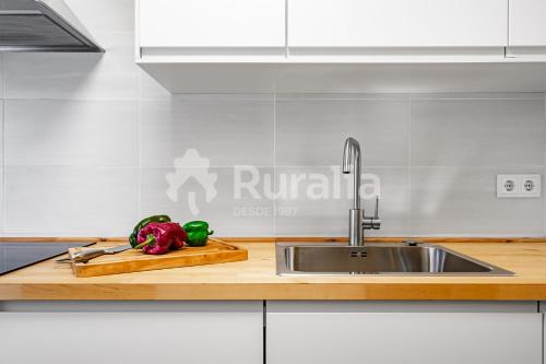 a kitchen counter with a sink and vegetables on a cutting board at QUINTA PORTIELLO Ribadesella in Ribadesella