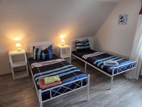 two beds in a small room with two lamps at Ferienwohnung, Urlaub im Frankenwald in Konradsreuth
