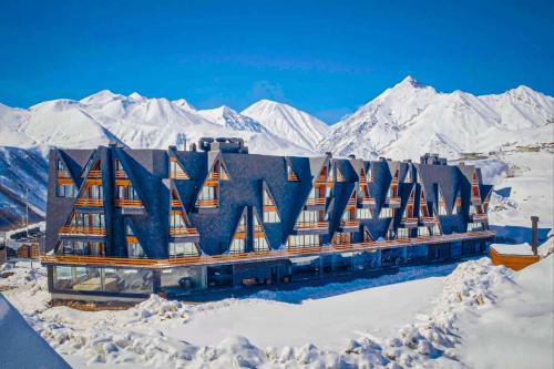 a building in the snow with mountains in the background at Comfy Studio in Gudauri Marshall - By Wehost in Gudauri