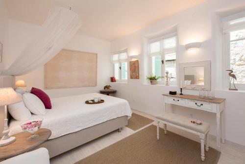 a bedroom with a bed with a desk and a mirror at White Jasmine Cottage in Áno Korakiána