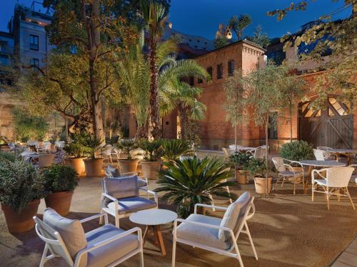un patio con mesas, sillas y palmeras en H10 Casa Mimosa 4* Sup, en Barcelona
