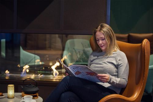 a woman sitting in a chair reading a book at Radisson Blu Polar Hotel, Spitsbergen in Longyearbyen