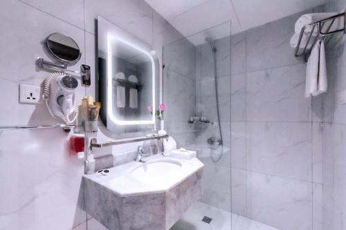 a white bathroom with a sink and a mirror at Palestine Hotel Makkah in Mecca