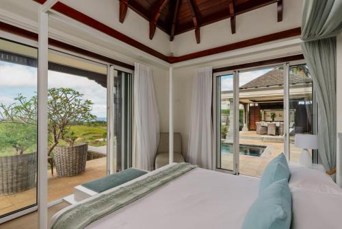 a bedroom with a bed and a large window at Heritage The Villas in Bel Ombre