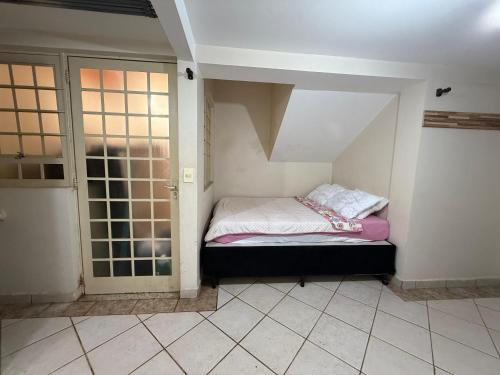 a small room with a bed and a door at Quarto em ótima localização in Botucatu