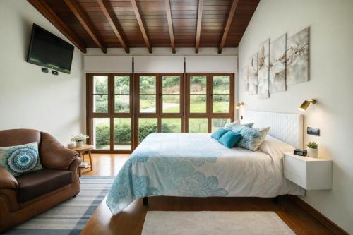 a bedroom with a bed and a couch and windows at Villa Senda Llanes – Jardín, Terraza y Playa Cerca in Llanes