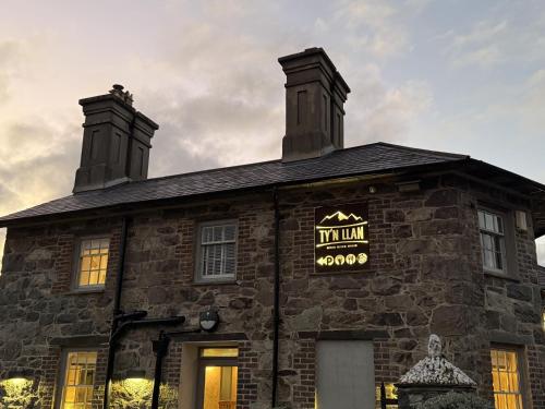 a stone building with a neon sign on it at Ty'n Llan- tafarn gymunedol- community pub in Llandwrog
