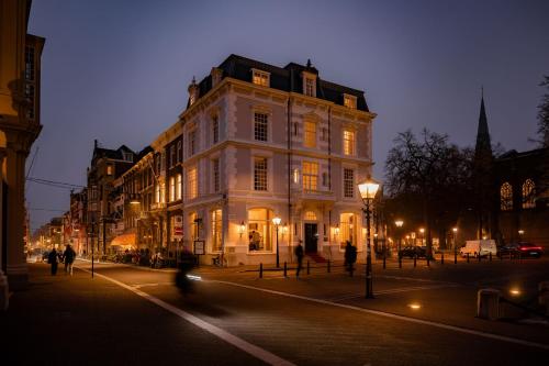 a large white building on a city street at night at ADAM & EVE Paleisstraat in The Hague