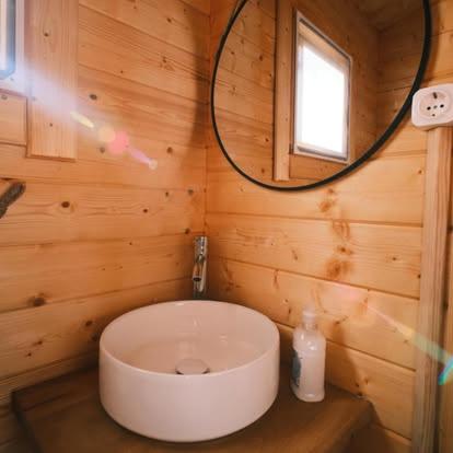 a bathroom with a white toilet in a wooden wall at Country Spot - Summer House in Porto Covo