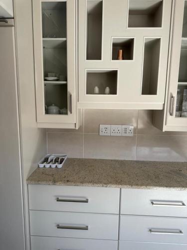 a kitchen with white cabinets and a counter top at Abebe Guest House in George
