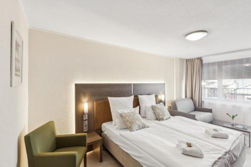 a hotel room with a large bed and a chair at Cityhotel Amadeus - 3 Sterne Superior in Münster
