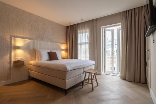 a bedroom with a bed and a large window at Hotel Zest Den Haag - Scheveningen in Scheveningen