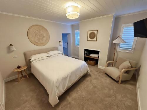 a bedroom with a white bed and a chair at Bathurst River House B & B in Bathurst
