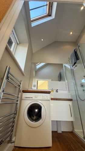 a washing machine in a bathroom with a shower at Little Park Farm Queen Anne Farmhouse & Apartments in Stratfield Mortimer