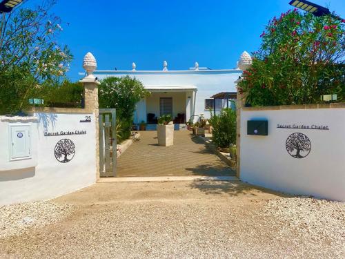 a white house with a gate and a driveway at Secret Garden Chalet No. 1 in San Pietro in Bevagna