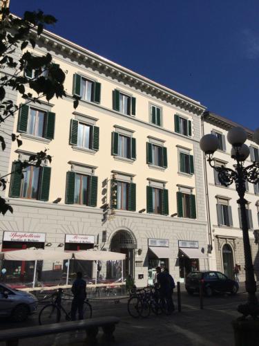 um grande edifício branco com janelas com persianas verdes em Hotel Caravaggio em Florença