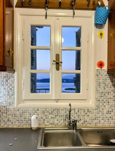 a kitchen with a sink and a window at Lime Andros Maisonette by HOSTANDROS in Apróvaton