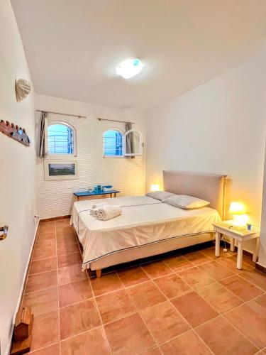 a bedroom with a large bed and two windows at Lime Andros Maisonette by HOSTANDROS in Apróvaton