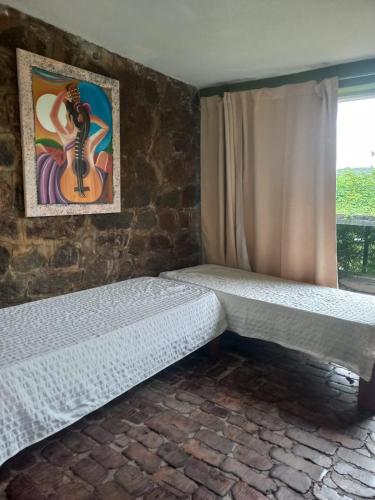 two beds in a room with a guitar on the wall at Tere & Tino Cabañas in Río Ceballos