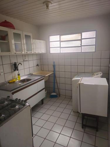 a kitchen with white tiled walls and white appliances at Apartamento Simples em Teresina com 02 Quartos in Teresina