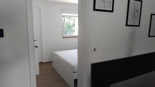 a white bedroom with a bed and a window at Vila Azzuro in Žusterna