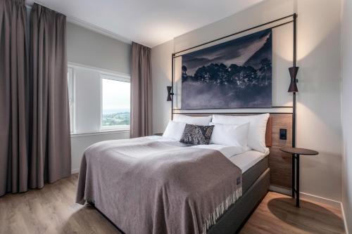 a bedroom with a bed with a large painting on the wall at Quality Hotel Edvard Grieg in Bergen
