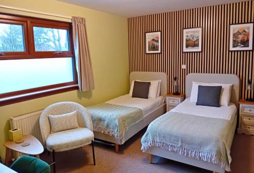 a bedroom with two beds and a chair and a window at Deveron Lodge B&B in Turriff