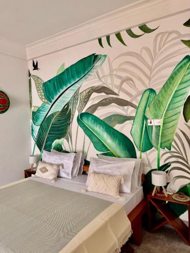 a bedroom with a bed with a mural of leaves at Olacoco by Olamanga in Jambiani