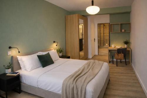 a bedroom with a large white bed and a desk at Appartements à Oloron in Oloron-Sainte-Marie
