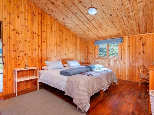 a bedroom with a bed in a wooden wall at Bloukrans Off-Grid Cabin in Montagu