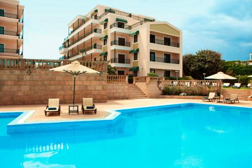 a swimming pool with two chairs and a building at Zeus Essence Ramada by Wyndham Athens in Mati