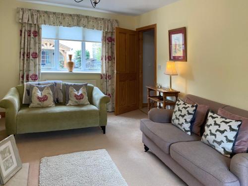 a living room with two couches and a window at Beckside Cottage in Bishop Monkton