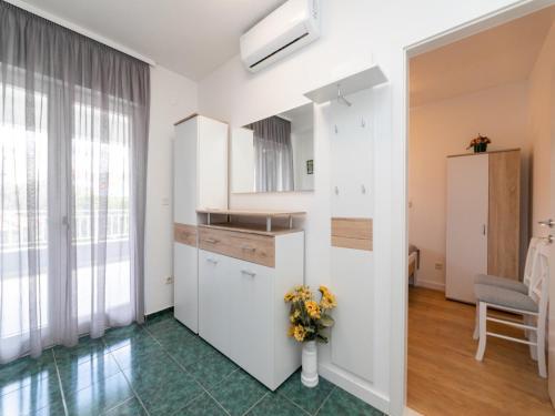 a kitchen with white cabinets and a vase of flowers at Villa Supe in Supetar