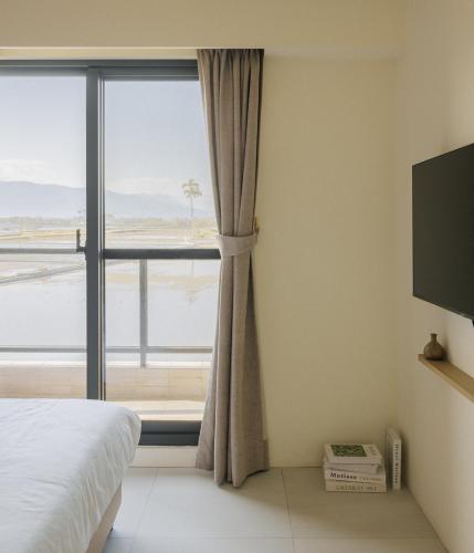 a bedroom with a bed and a large window at 參穗 SunSui Guesthouse in Sanxing