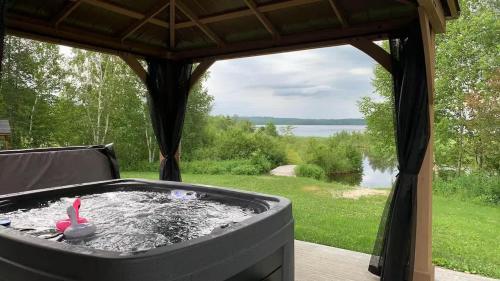 a hot tub in a gazebo with a view of a lake at Spa & Kenogami Lake - Chalet le Rustik in Saguenay