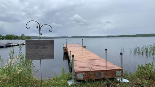 a dock in the middle of a lake with a sign at Spa & Kenogami Lake - Chalet le Rustik in Saguenay