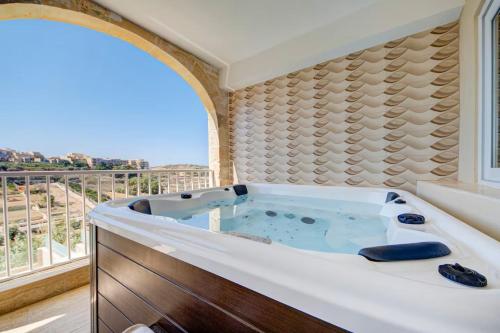 a bath tub in a room with a window at Gozo Getaway! Heated Jacuzzi & Views in Xagħra